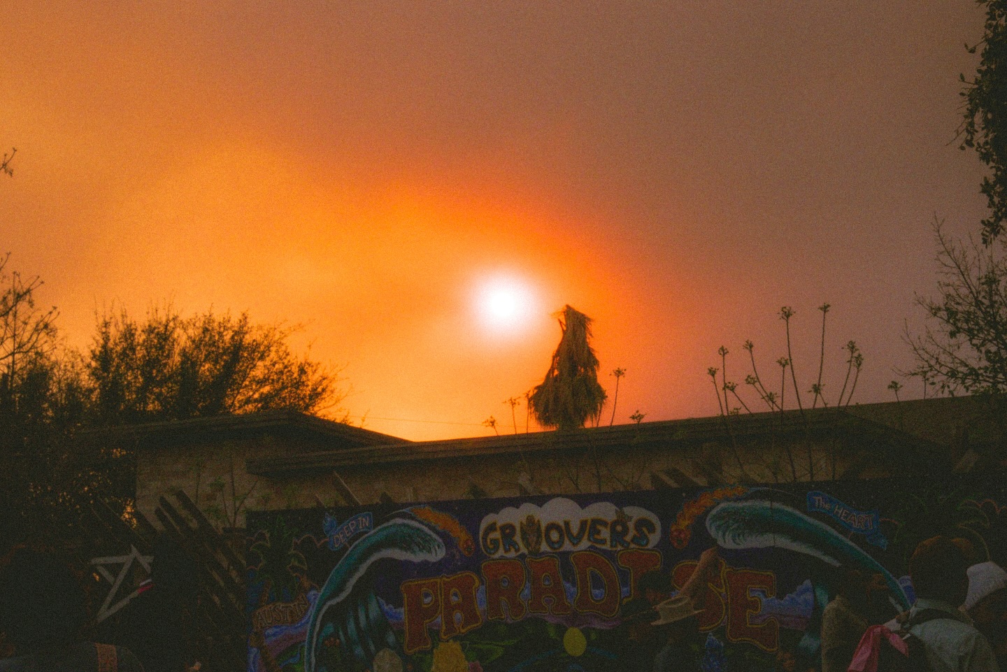 Orange smoky sky over a graffiti-covered wall