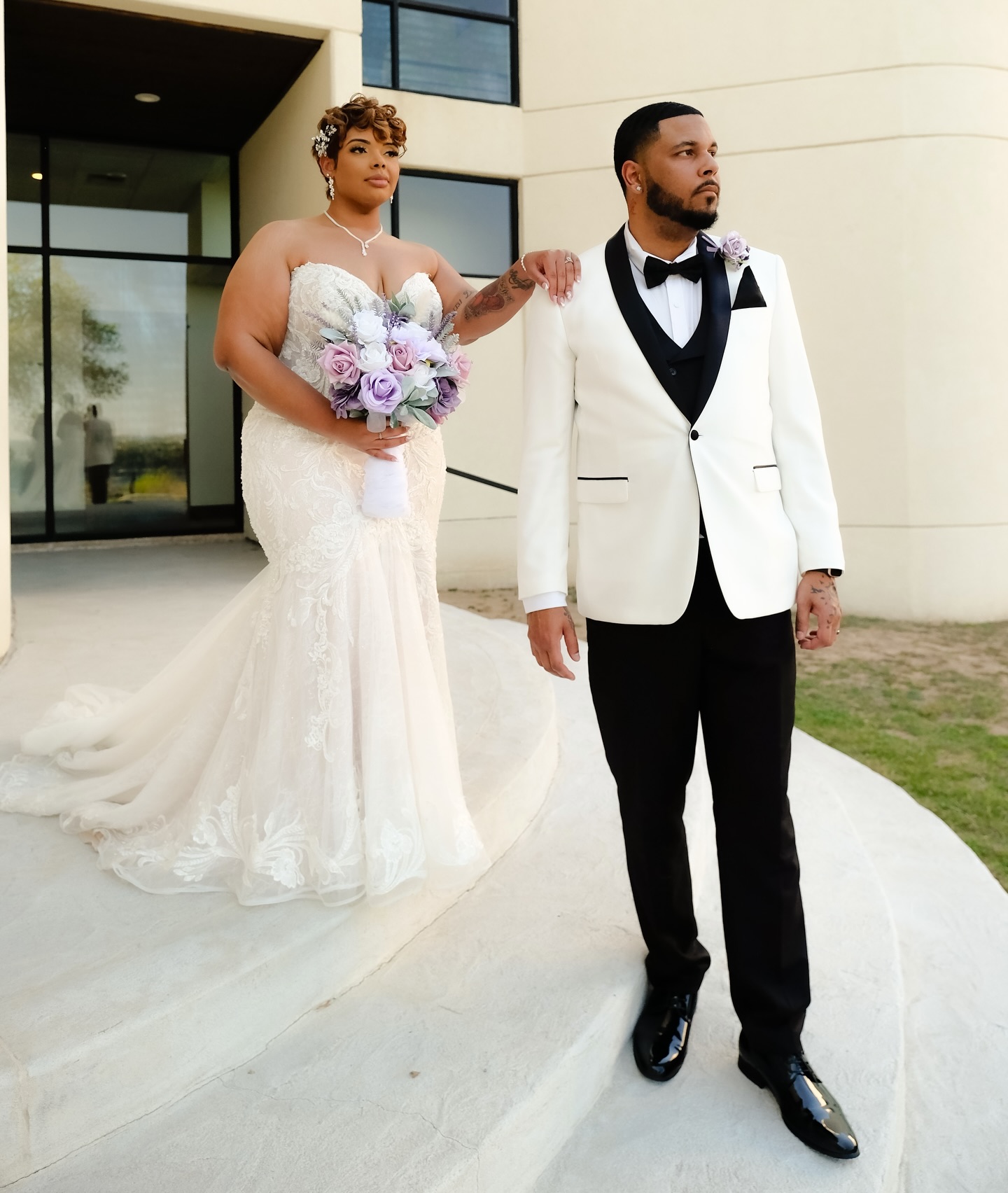 A couple in wedding attire standing outside a building