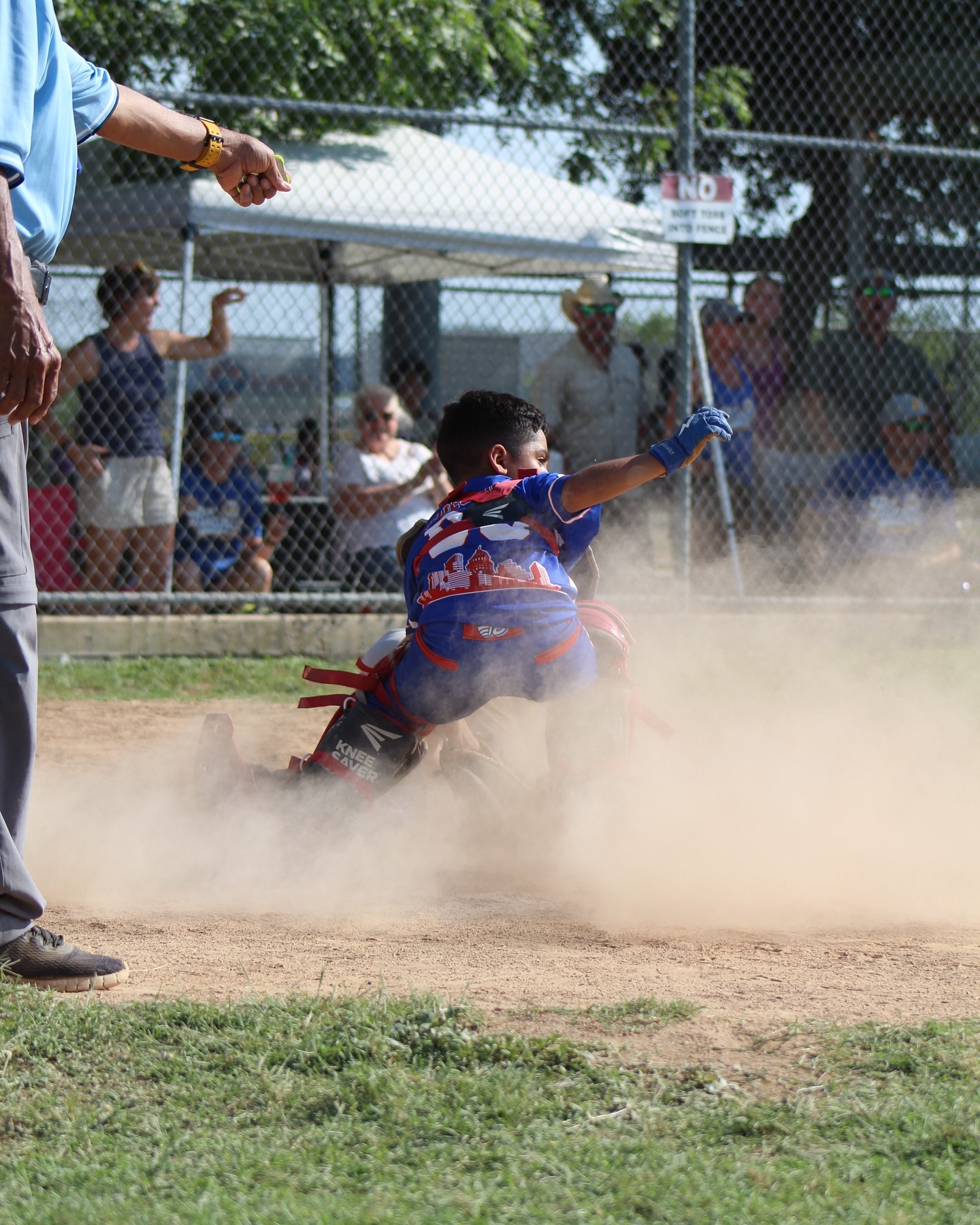 Kid sliding into base in a cloud of dust at a baseball game