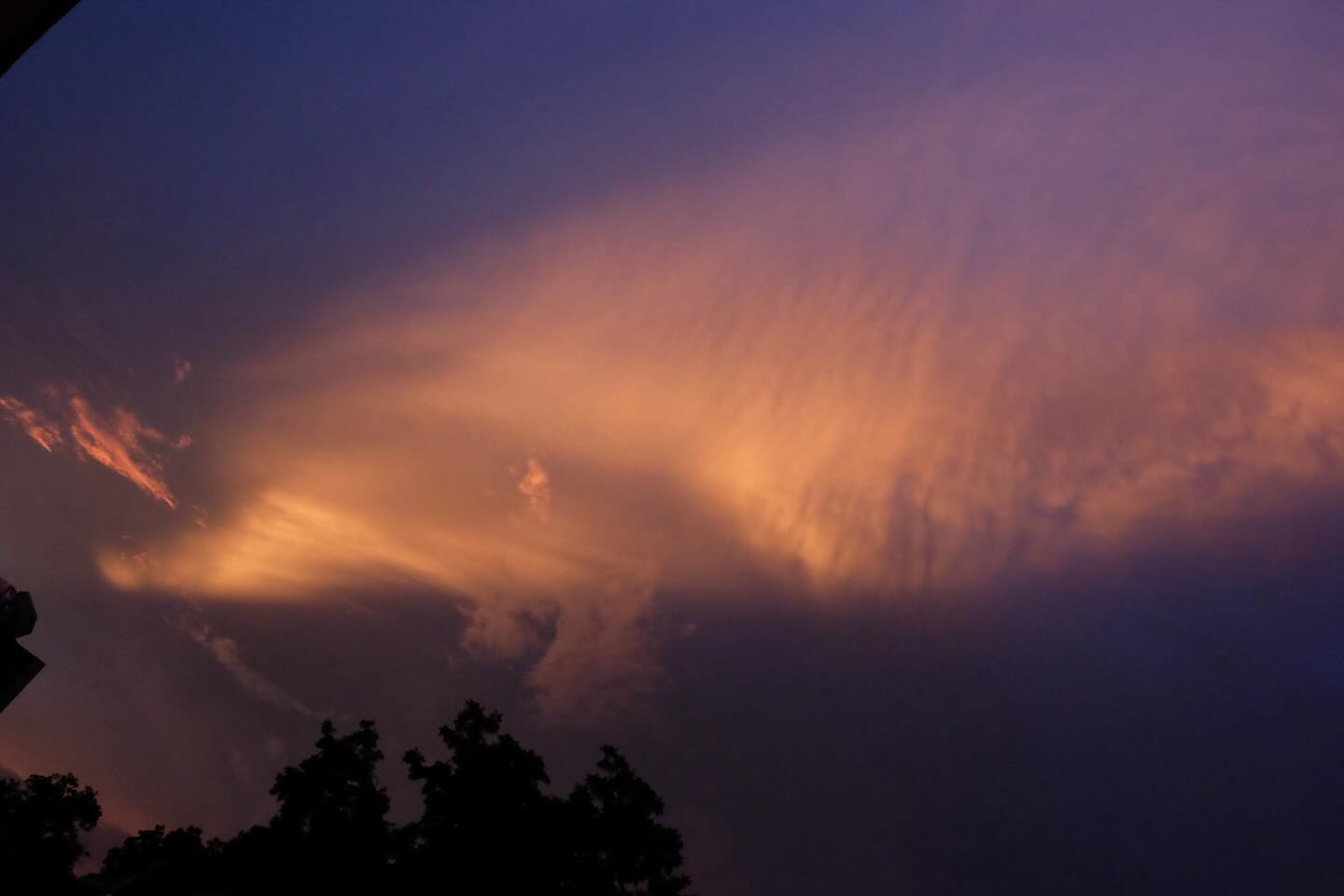 Orange glowing clouds at dusk above silhouetted trees