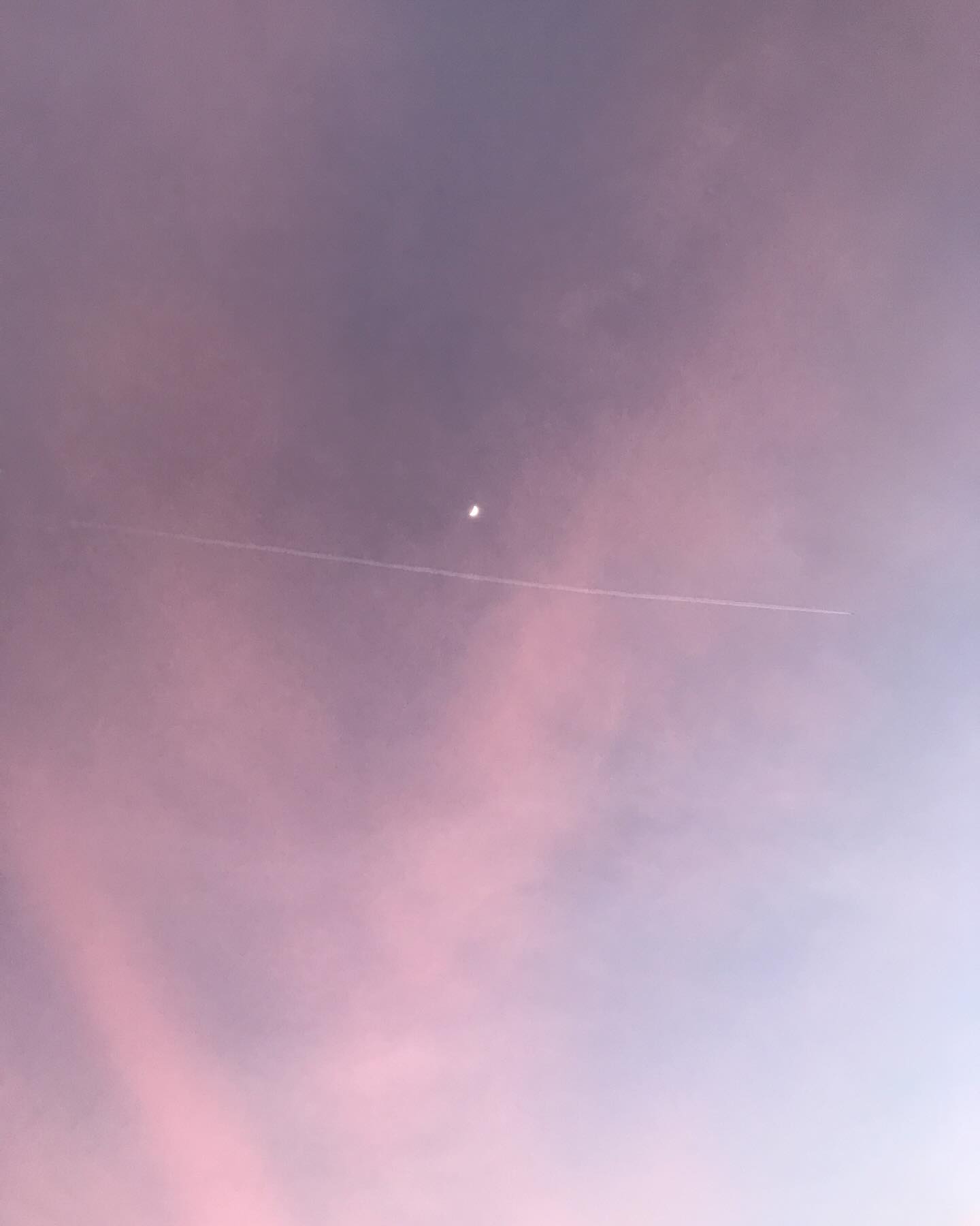 Pink dusk sky with a small plane trail