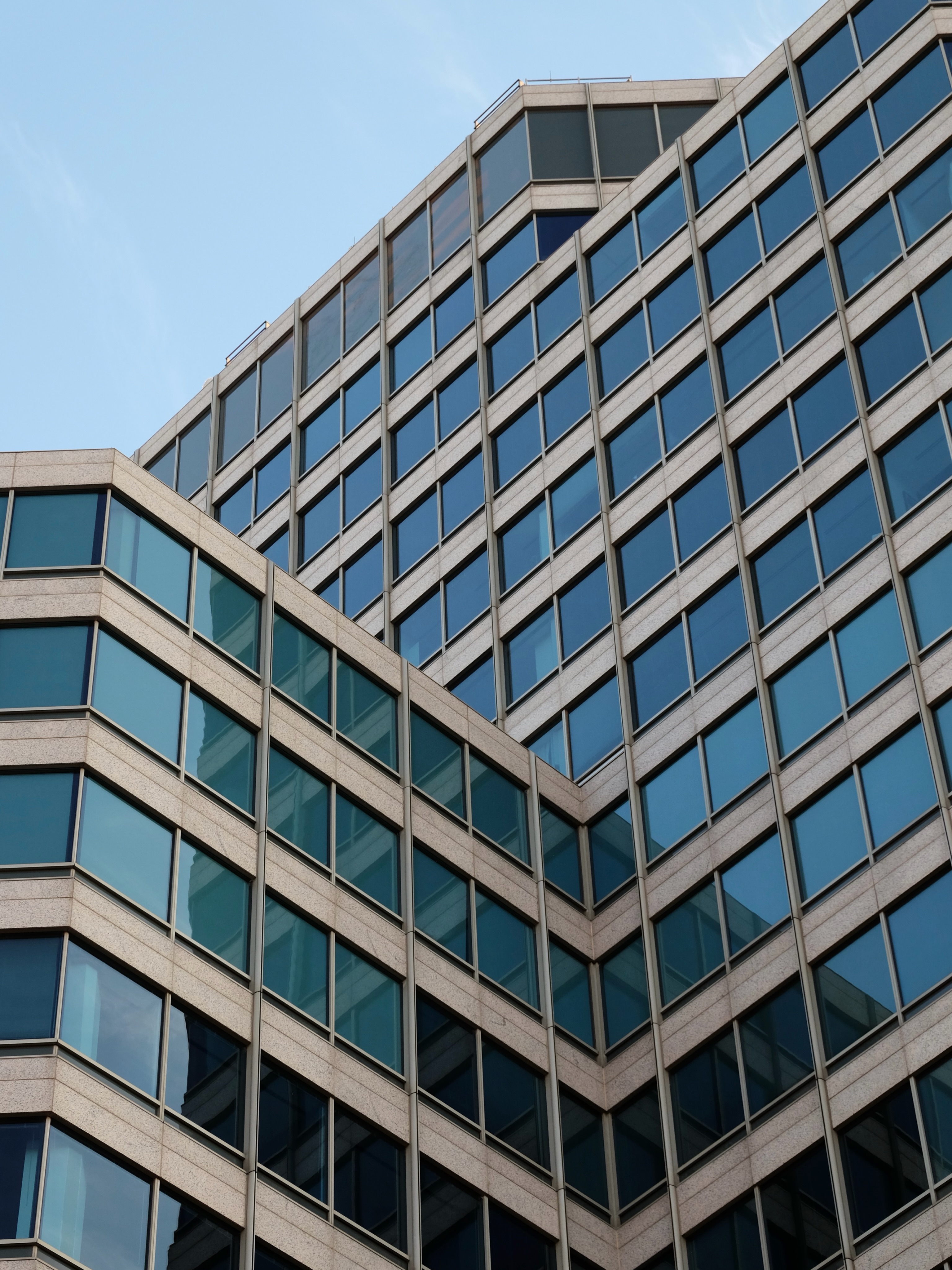 Angled glass and concrete office building against a blue sky