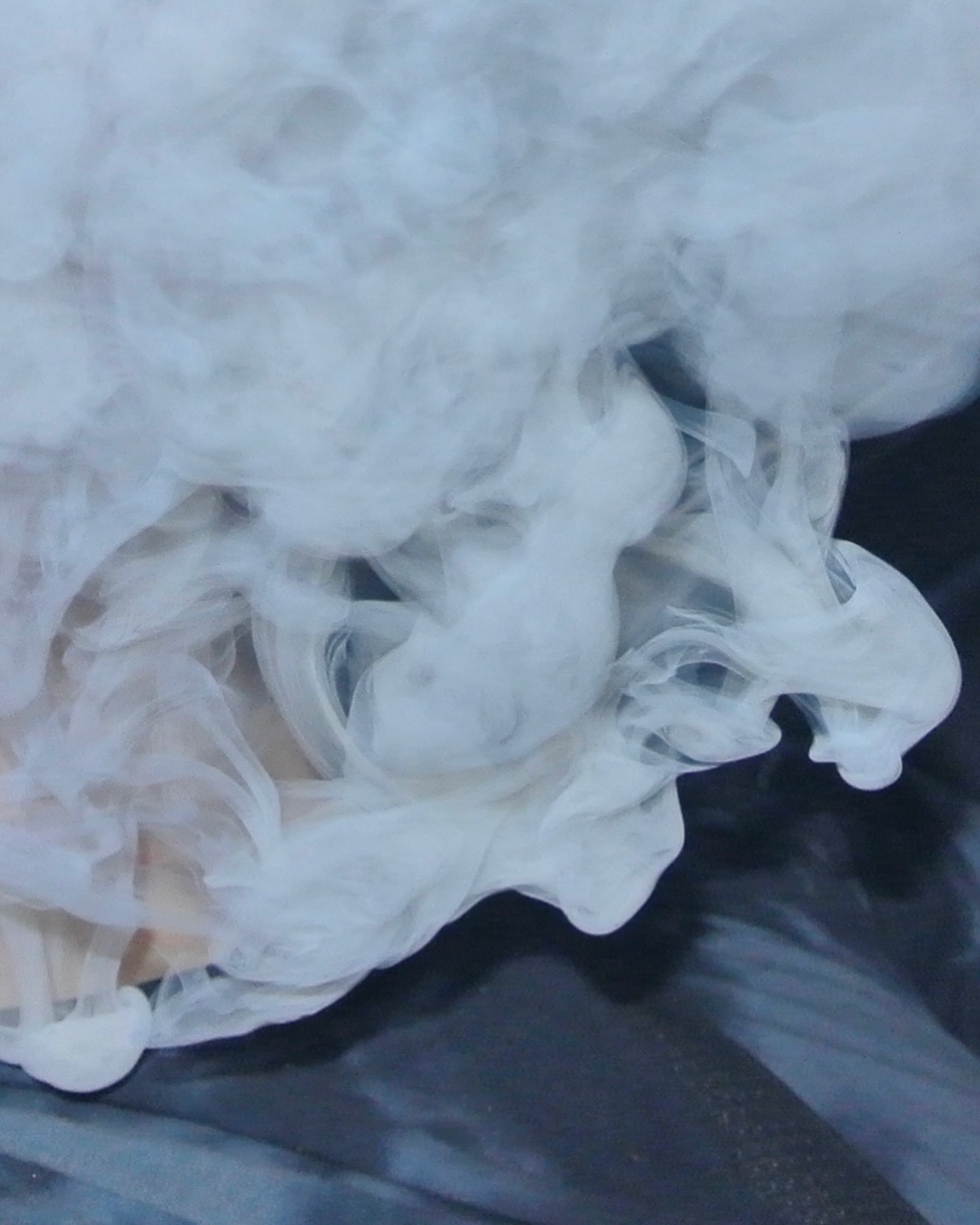 Soft white smoke curling against a dark fabric background